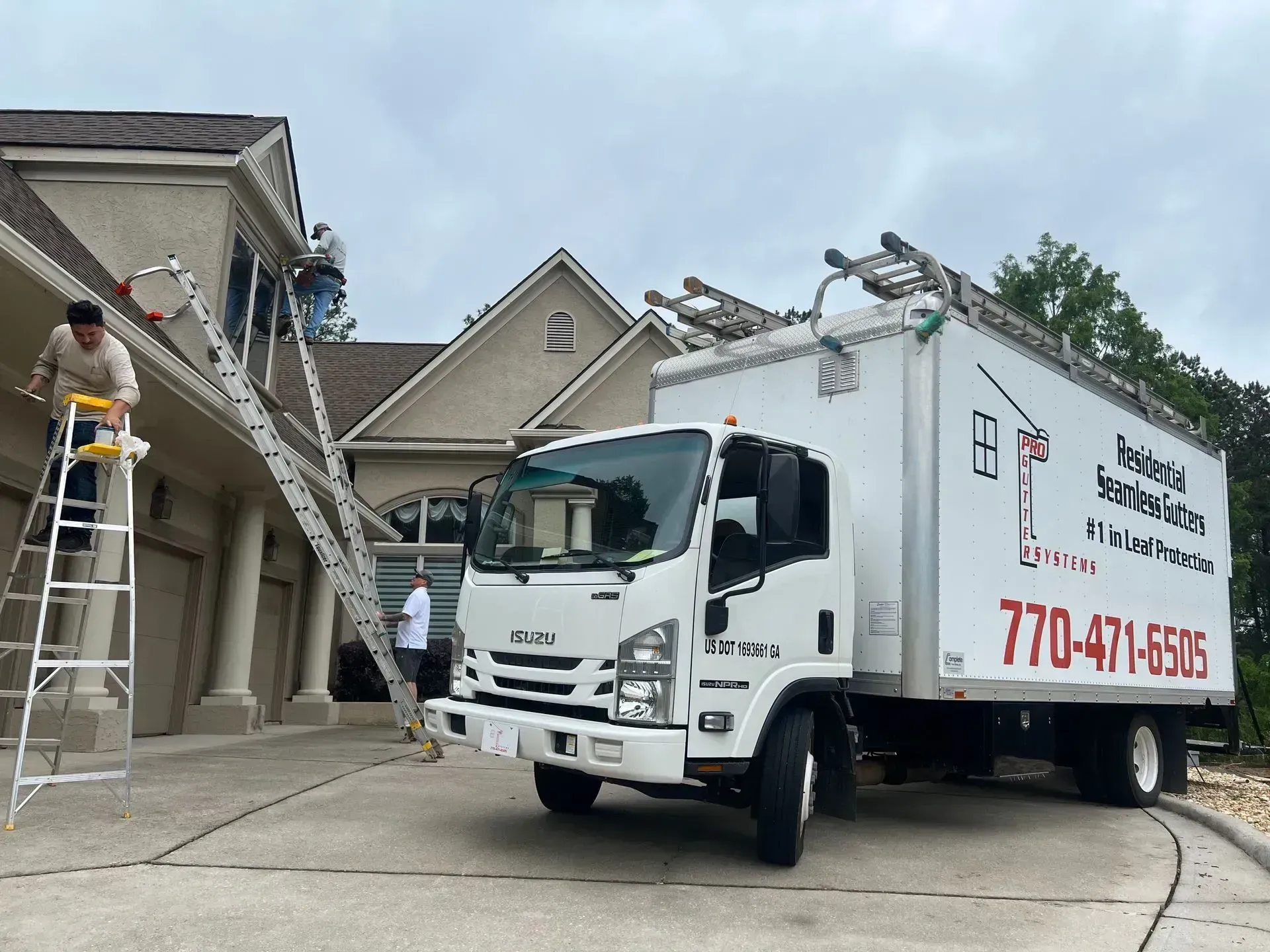 Workers unloading a moving truck at a suburban house with a ladder extended to the roof