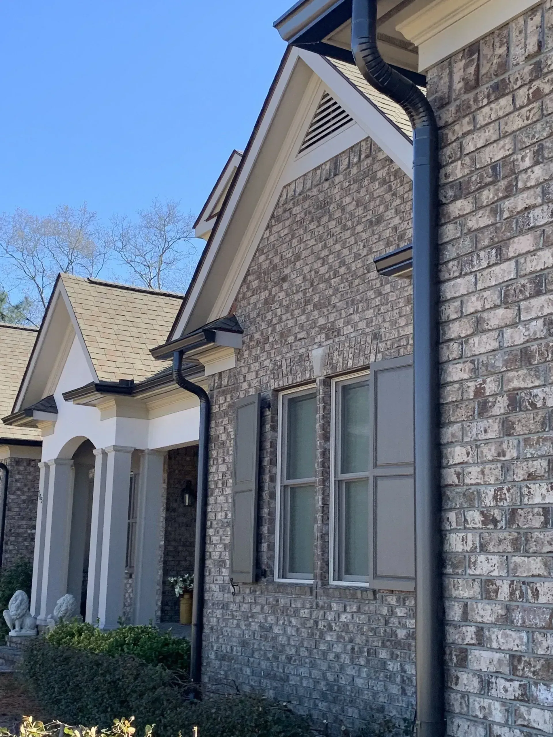 Row of suburban brick houses with beige roofs and white columns under a clear blue sky