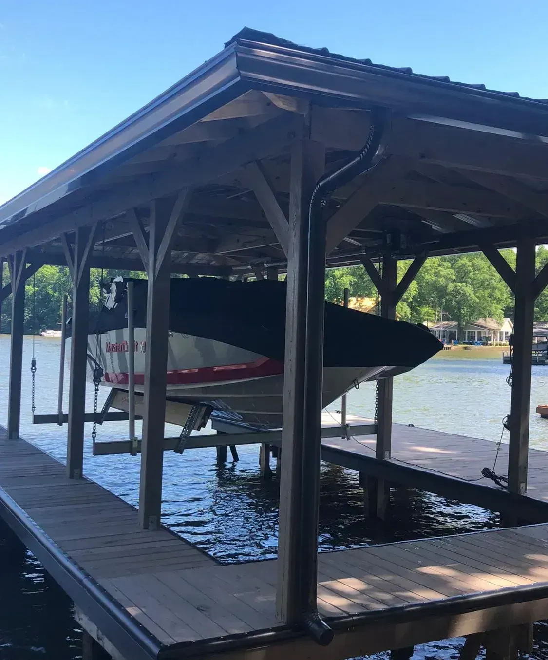 Boat docked in a covered wooden boathouse on calm water, with a red-and-black canoe visible.