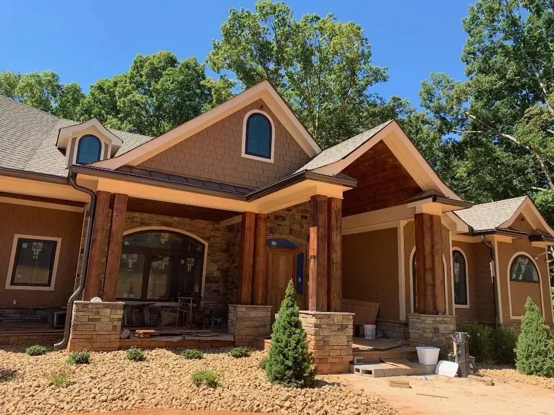 Rustic wooden house with a porch and stone accents under a clear blue sky