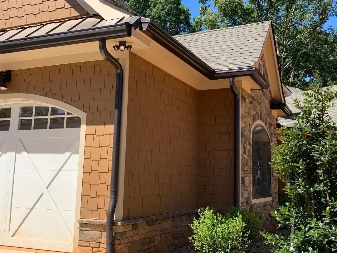 Tan stucco house with white garage door, brick trim, and tiled roof under a blue sky