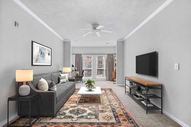 Living room with gray walls, sofa, and TV. Rug, coffee table, desk, and window.