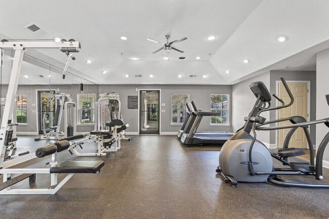 Gym interior with exercise machines, including treadmills, weights, and stationary bikes.