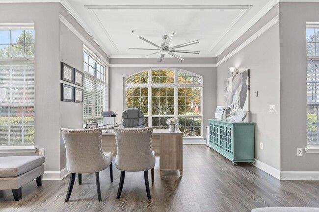 Home office with large windows, wooden floors, grey walls, and a teal cabinet.