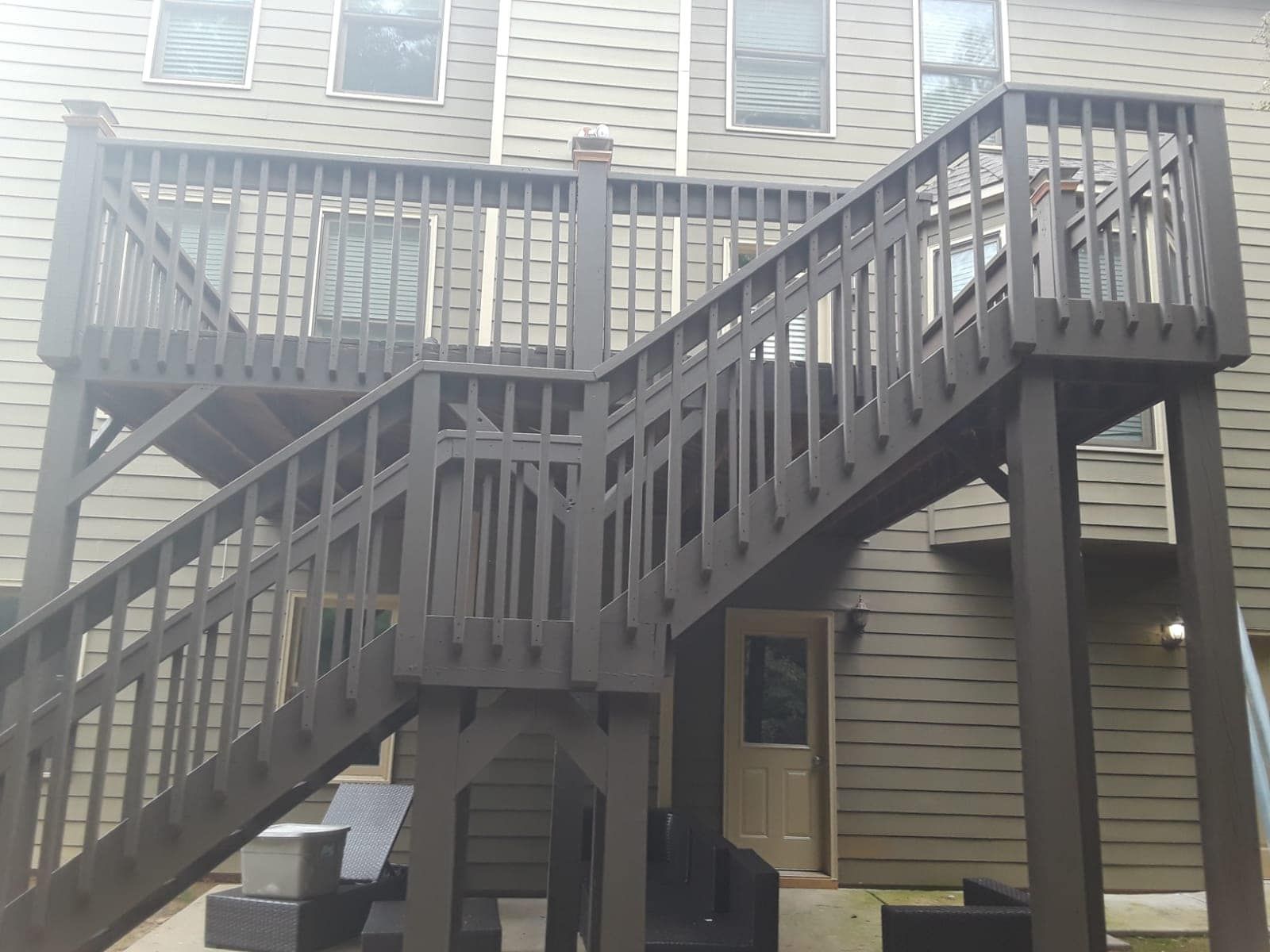 Wooden exterior staircase and deck on a beige house with multiple windows
