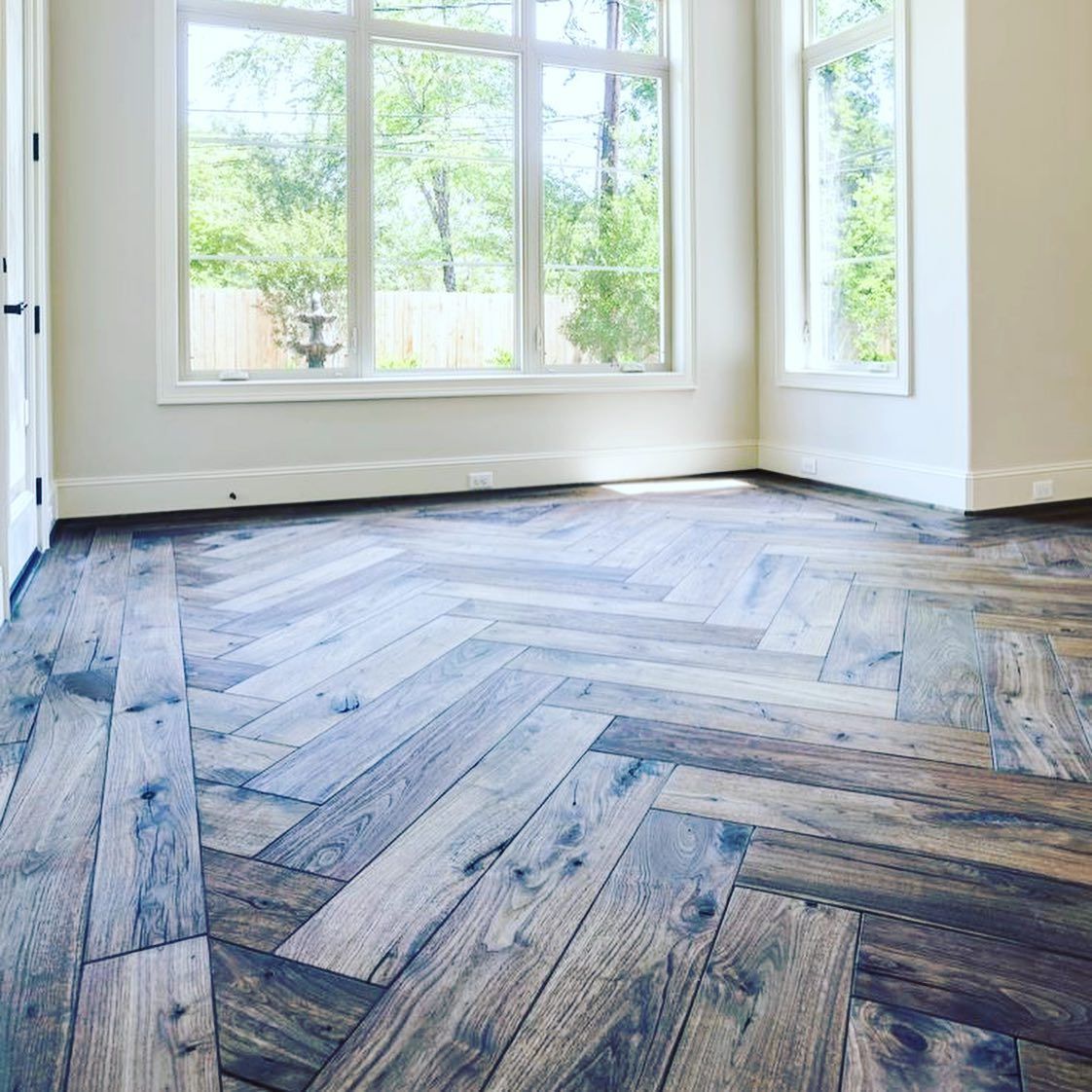 Bright empty room with large windows and herringbone wood floor