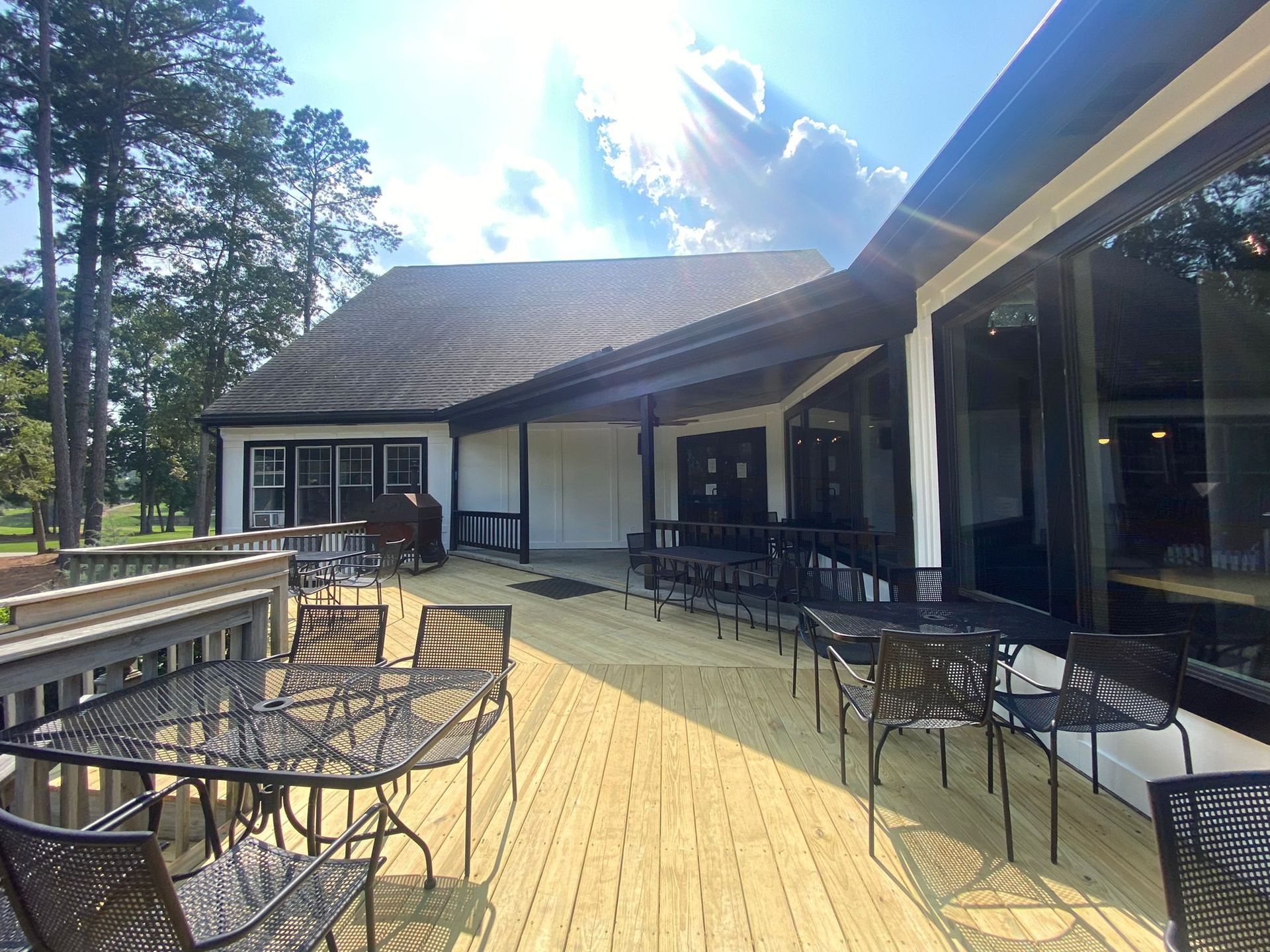 Outdoor patio with black metal tables and chairs beside a lodge-like building under a bright sky