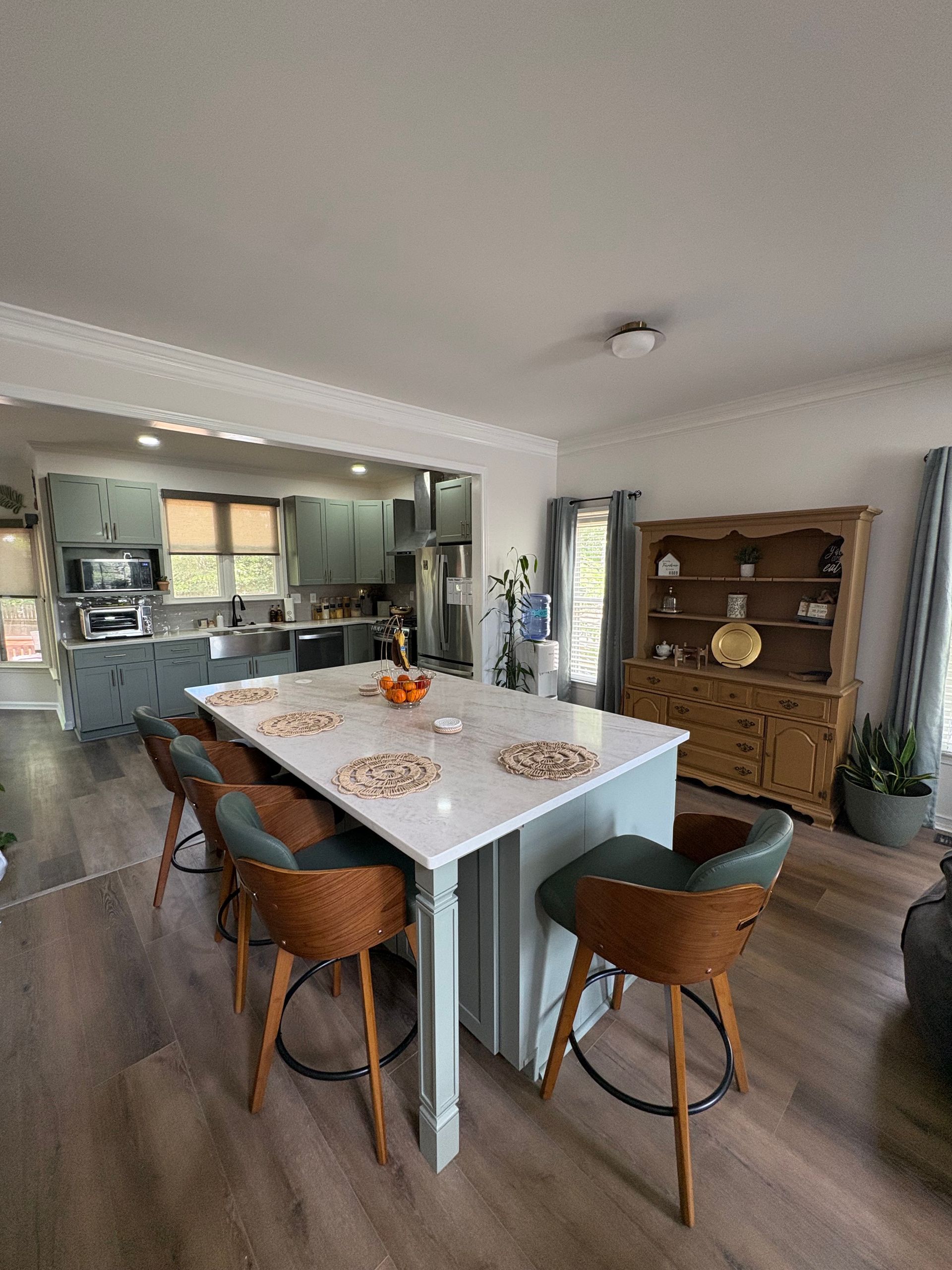 Modern kitchen and dining area with a white island, brown chairs, and wood floor