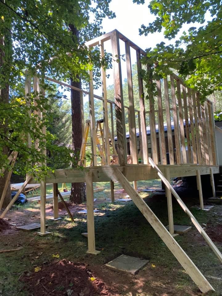 Wooden deck frame under construction in a wooded backyard, with support posts and diagonal braces
