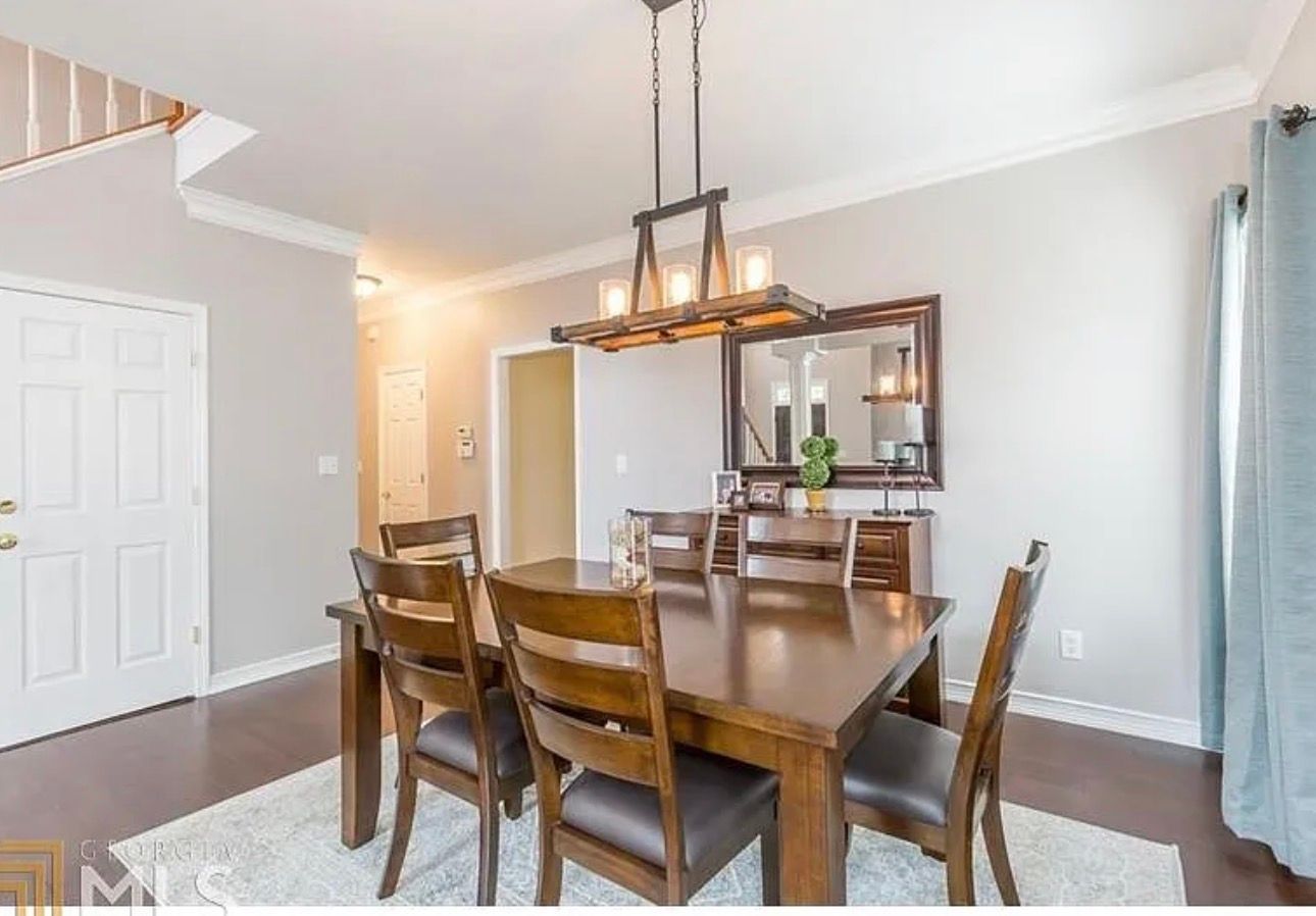 Dining room with wooden table, chairs, and chandelier in a light gray home interior
