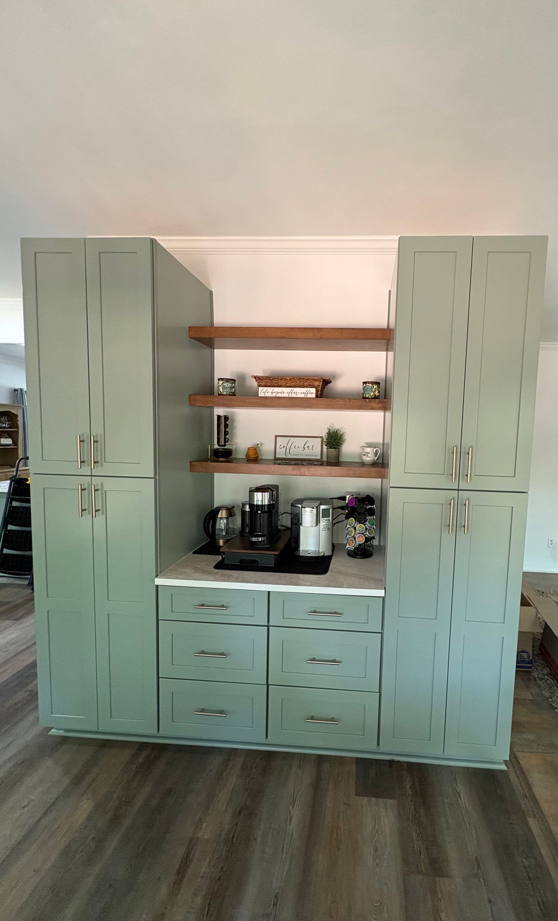 Mint green kitchen hutch with drawers, shelves, and coffee maker against a wall.
