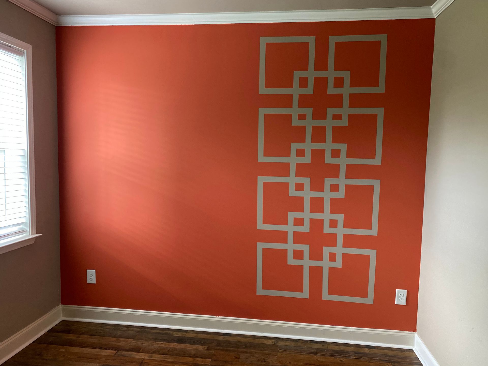 Empty room with coral accent wall and geometric square wall stencil pattern