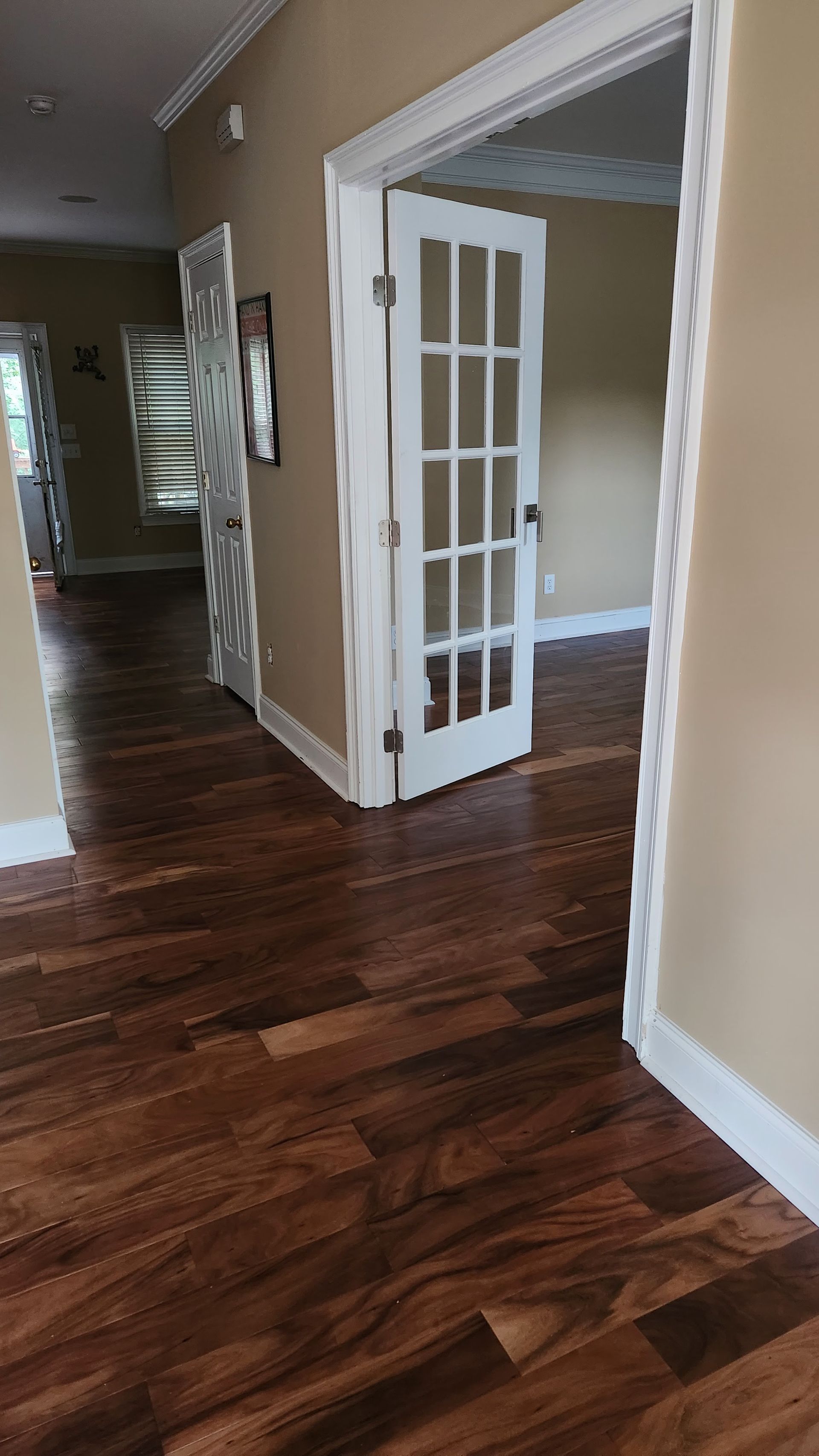Hallway with dark wood floors and white French doors leading into a room.