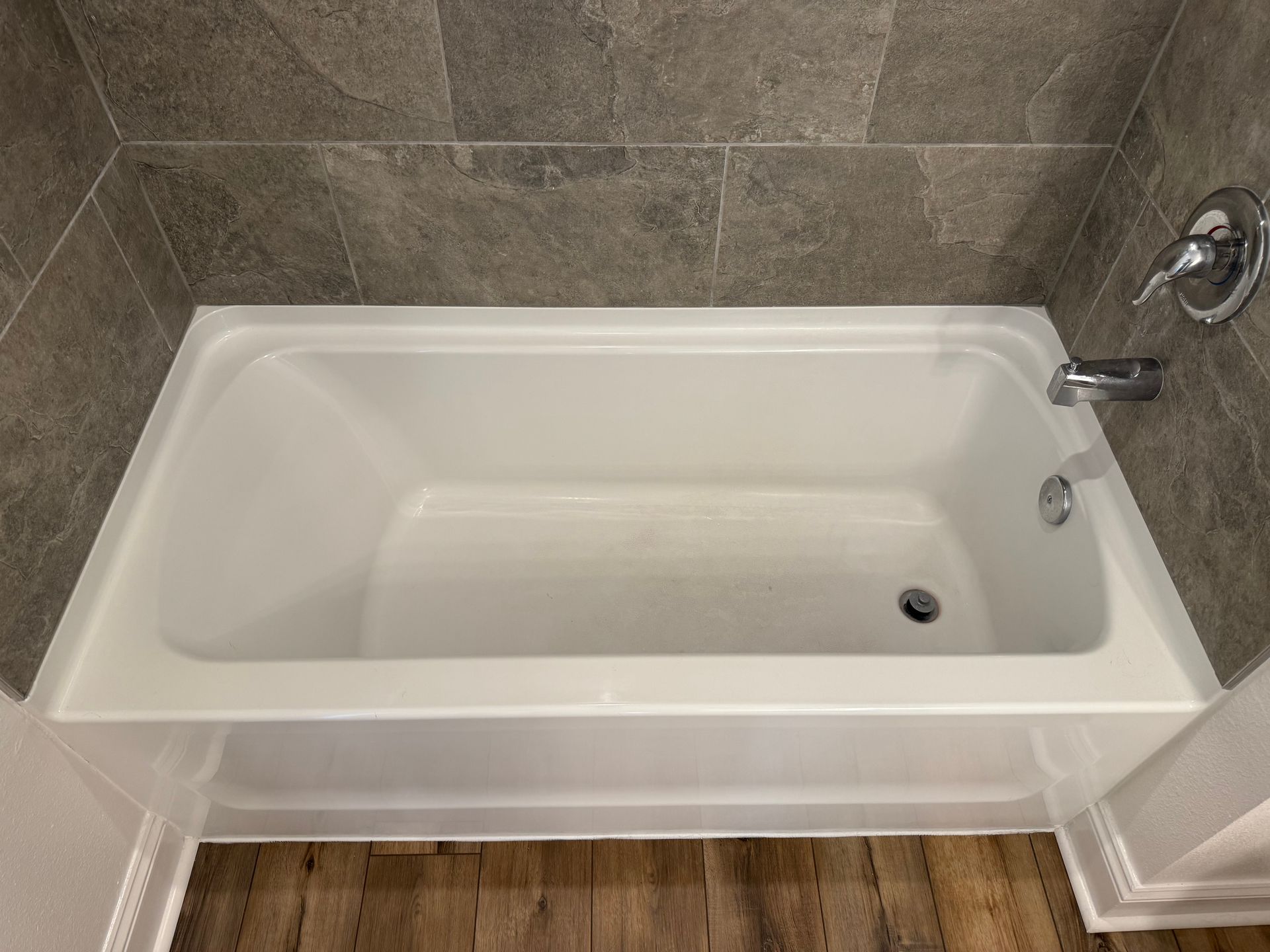 White bathtub with chrome faucet in a tiled bathroom nook