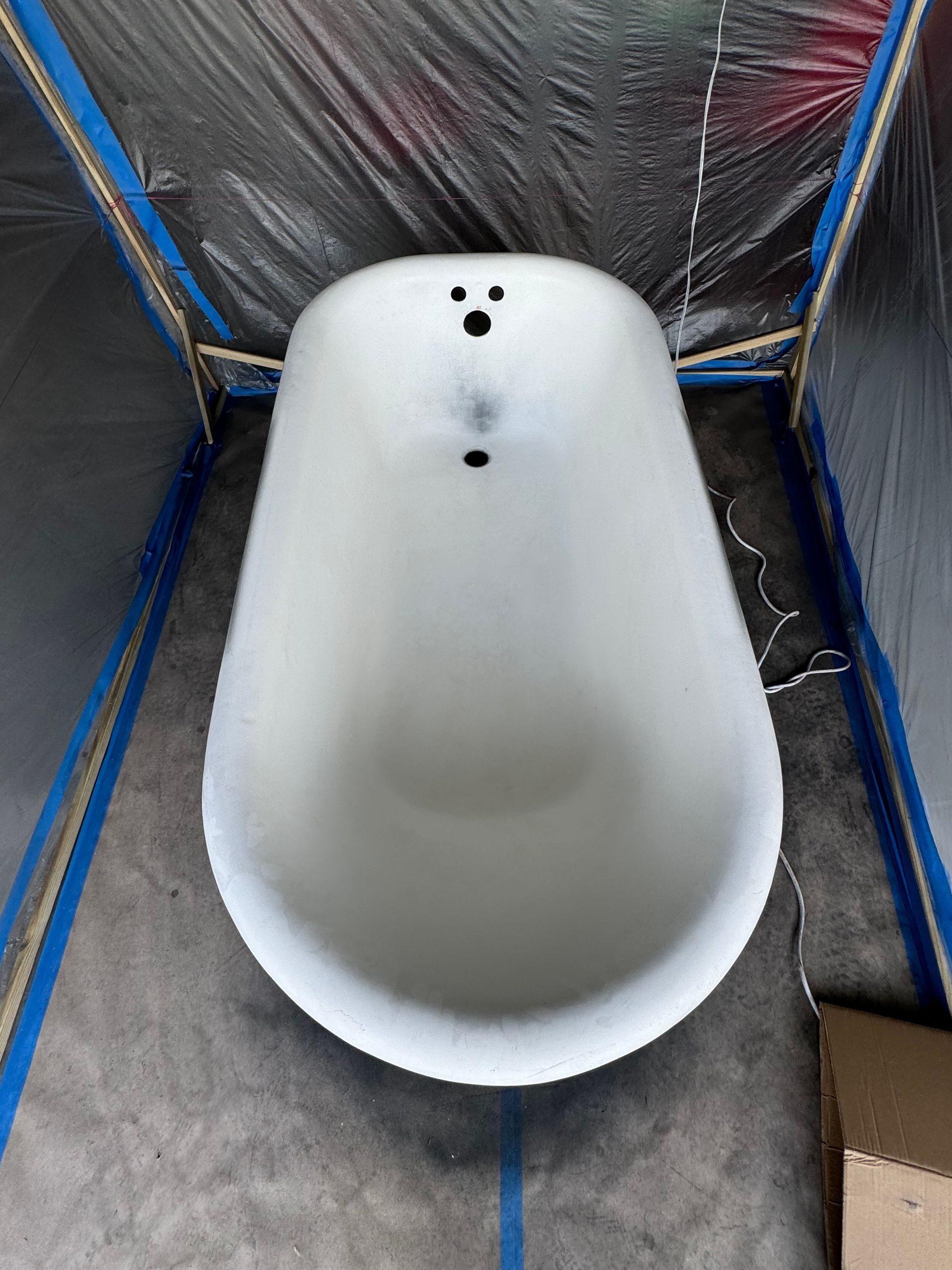 White bathtub in a small tiled room with reflective insulation walls