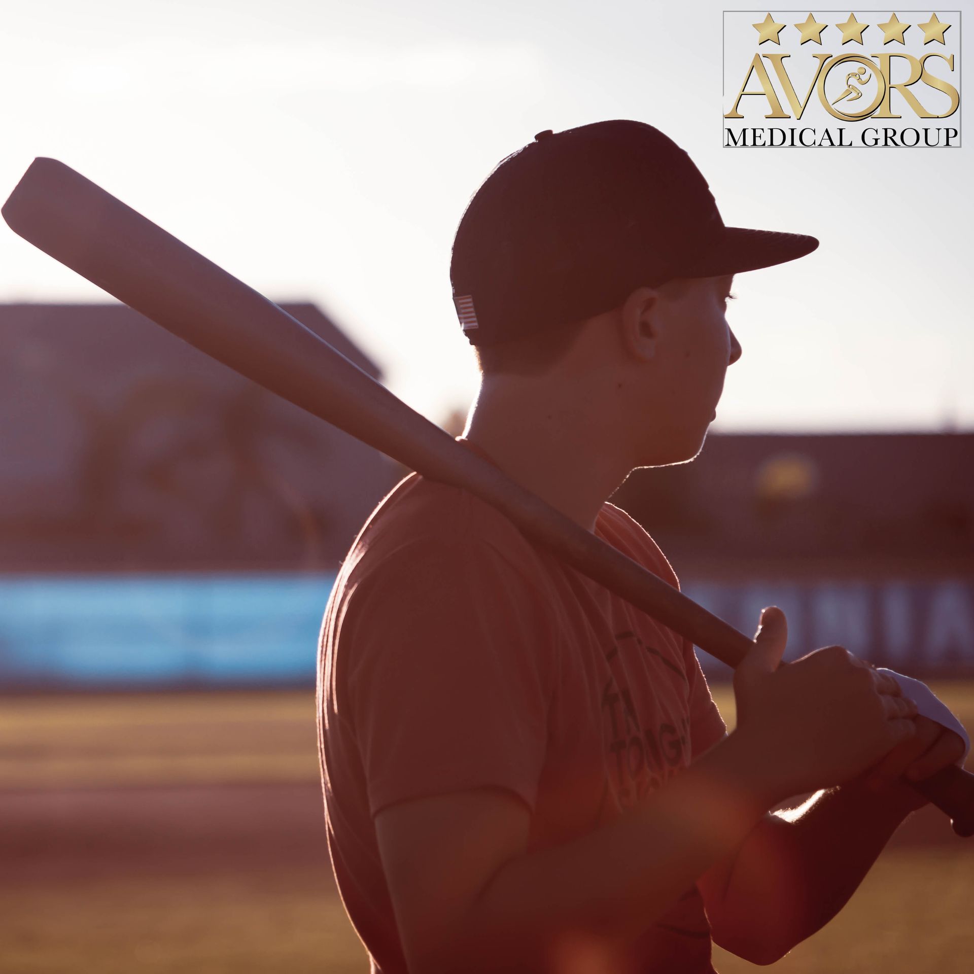 Person in baseball cap, holding a bat on shoulder, looking out at a field.
