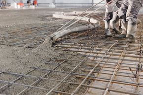 Workers pouring concrete over steel rebar at a construction site