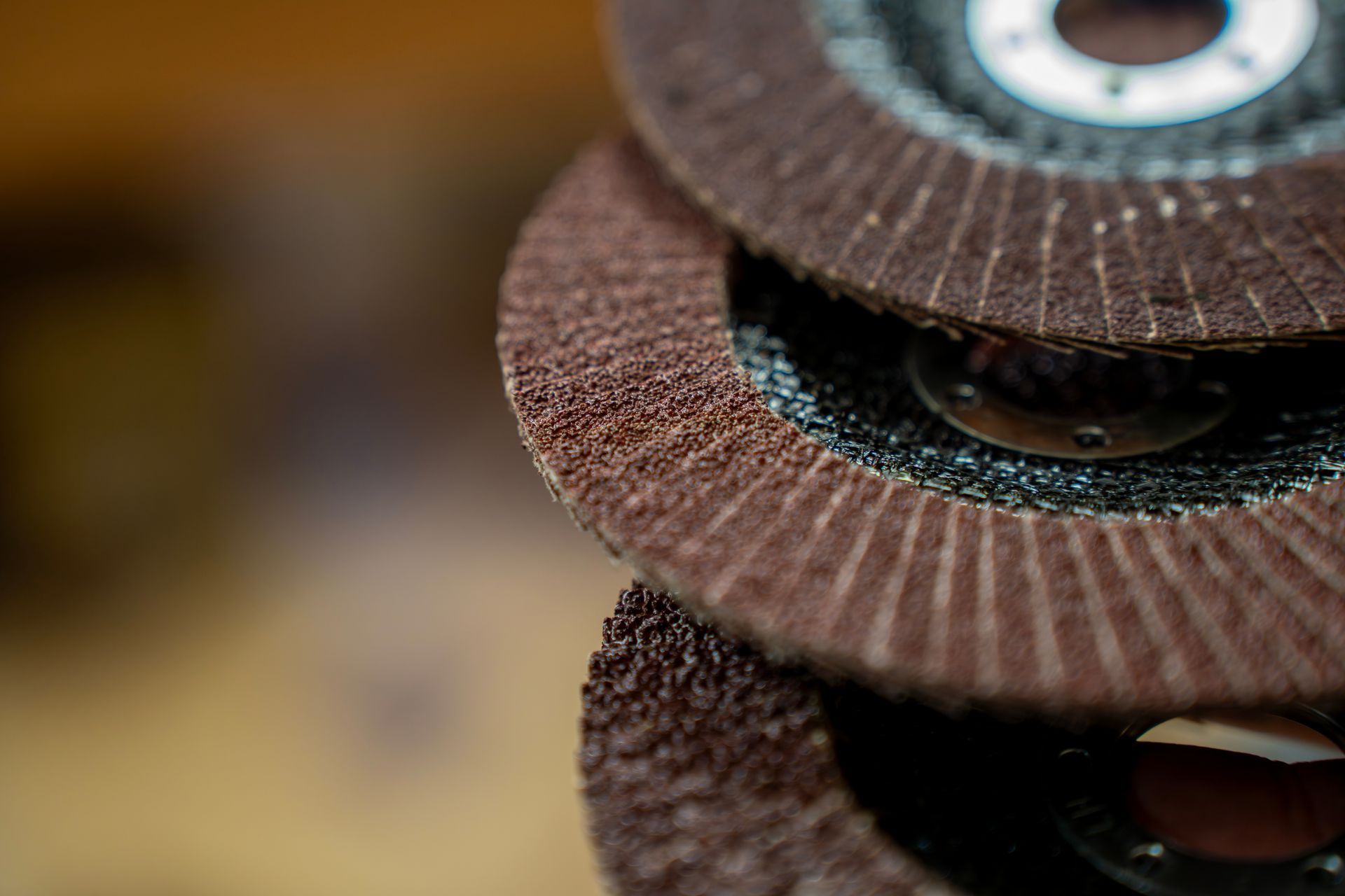 Close-up of layered flap abrasive discs, showing rough sanding material and circular metal centre. Close-up of layered flap abrasive discs, showing rough sanding material and circular metal centre.