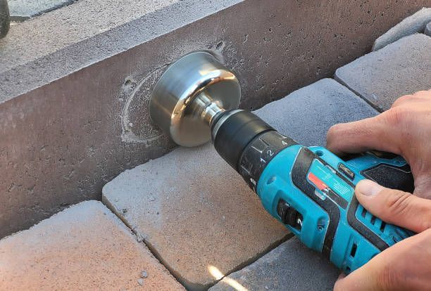 A person is using a drill to drill a hole in a brick wall.