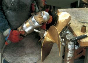 A man is grinding a propeller with a grinder.