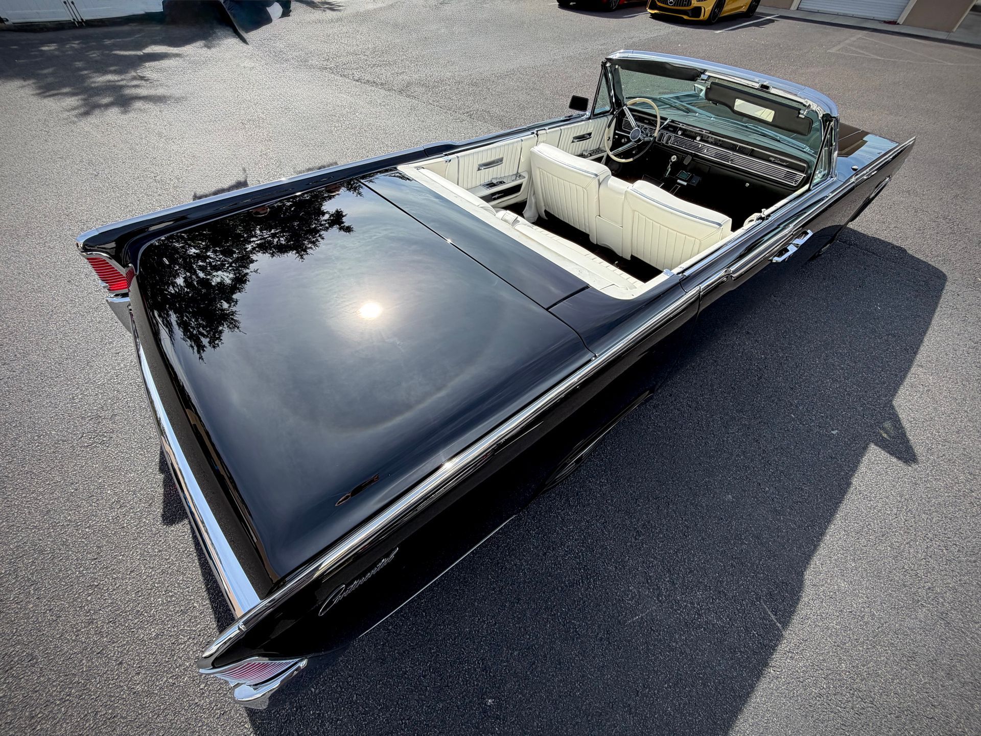 Black classic convertible car with white interior parked on asphalt.