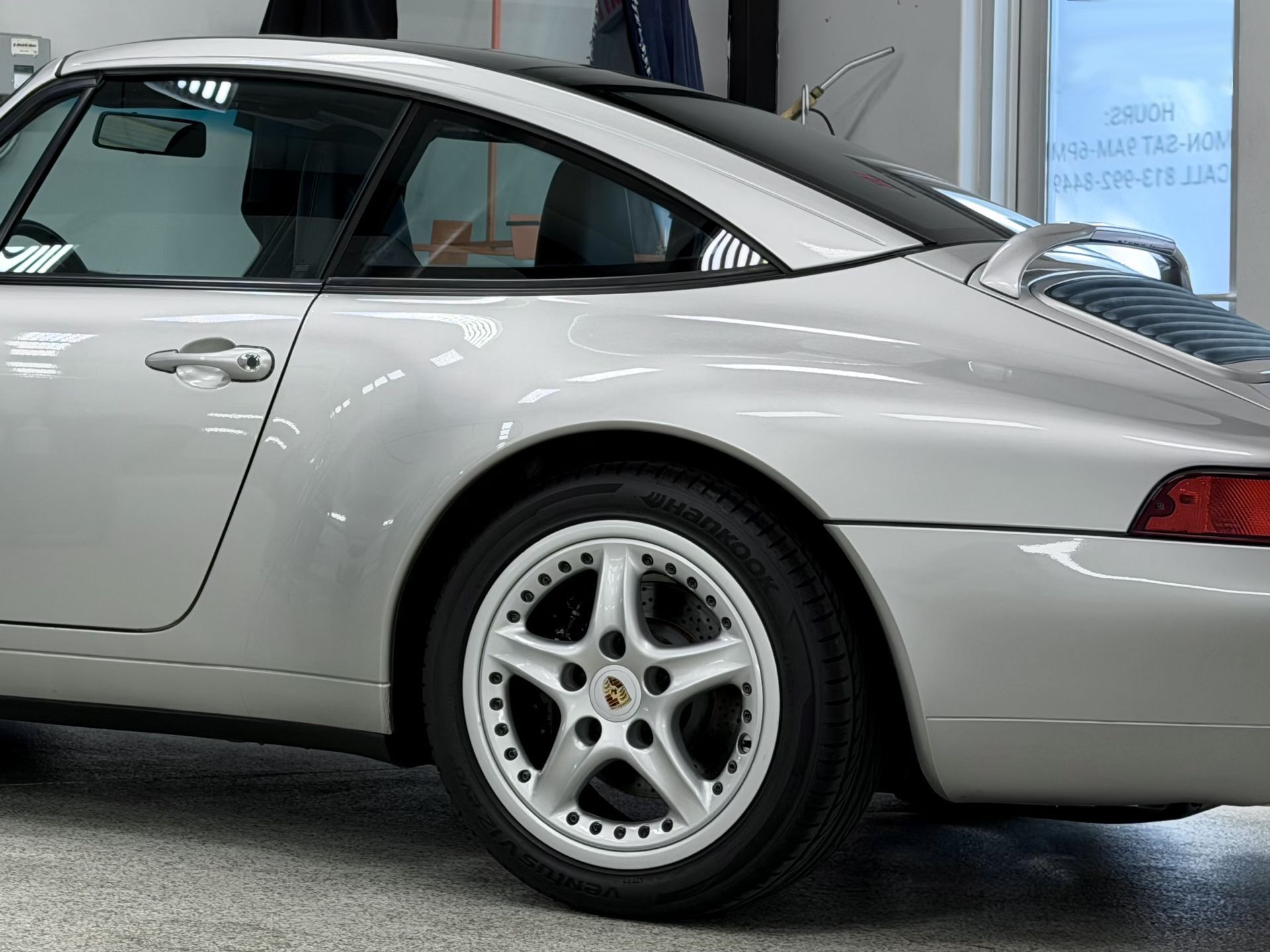 Silver Porsche 911 Targa car, rear quarter view, with a black roof and silver wheels.