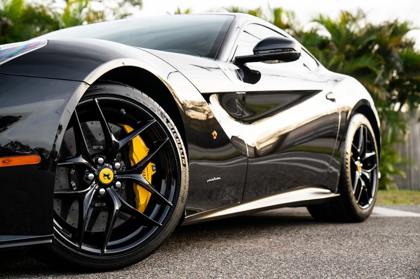 A black sports car with yellow brake calipers is parked on the side of the road.
