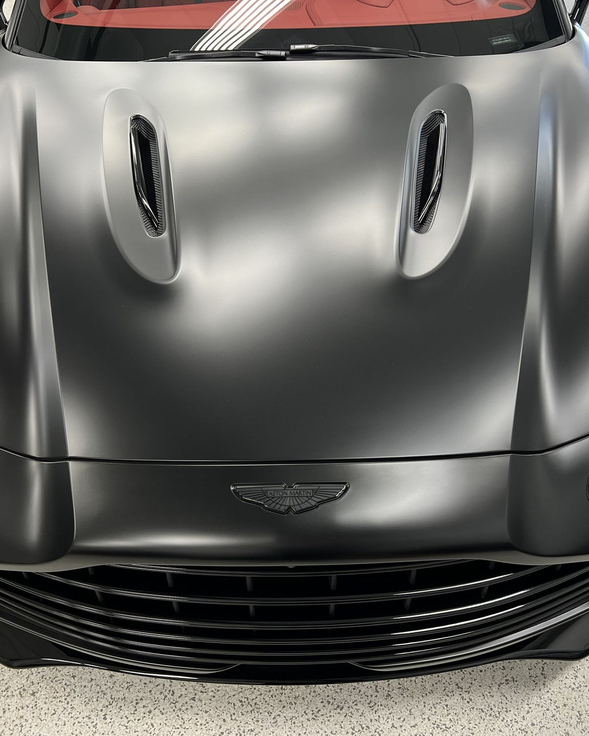 Front view of a black Aston Martin sports car with a hood vent and silver grille