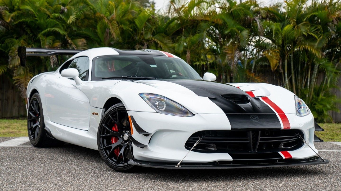 White Dodge Viper sports car with black racing stripes and red accents parked outdoors.
