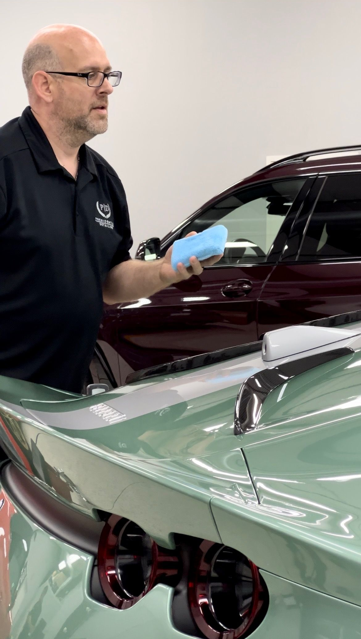 Mechanic tightening a wheel lug nut on a red car in a garage