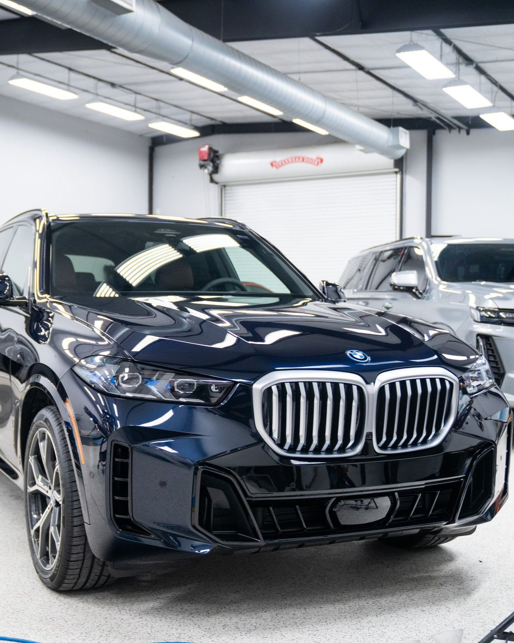 Dark blue BMW SUV in a bright indoor showroom with another car in the background