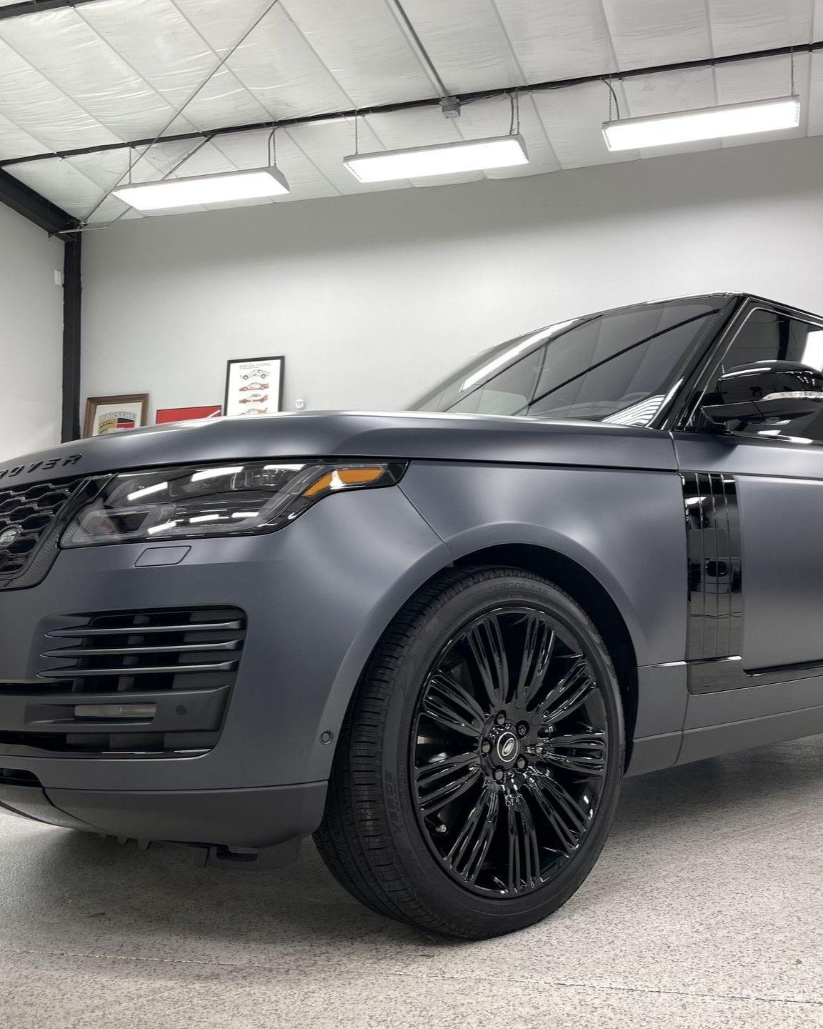Dark gray luxury SUV in a bright auto shop, shown from the front-left with black wheels.