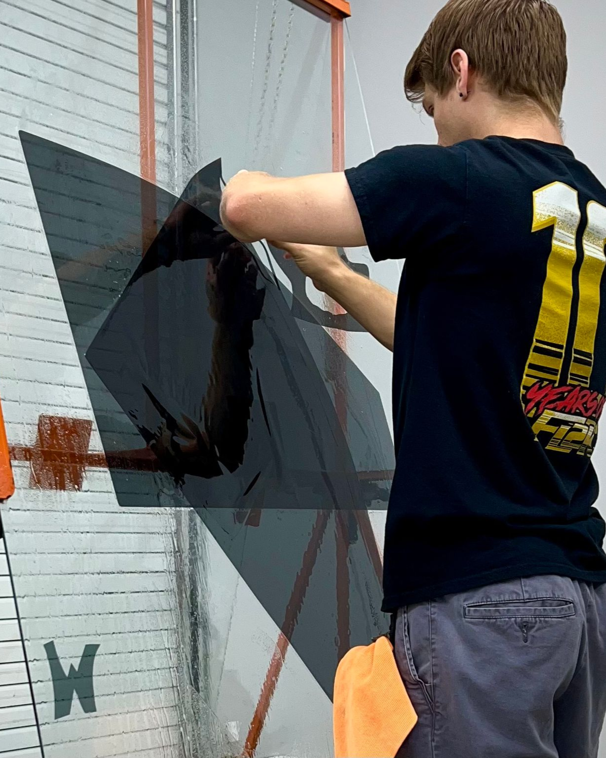 Person applying dark window film to a storefront window