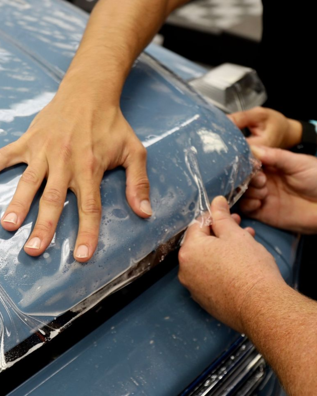 Hands pressing and smoothing a blue vinyl cushion or seat cover during repair.
