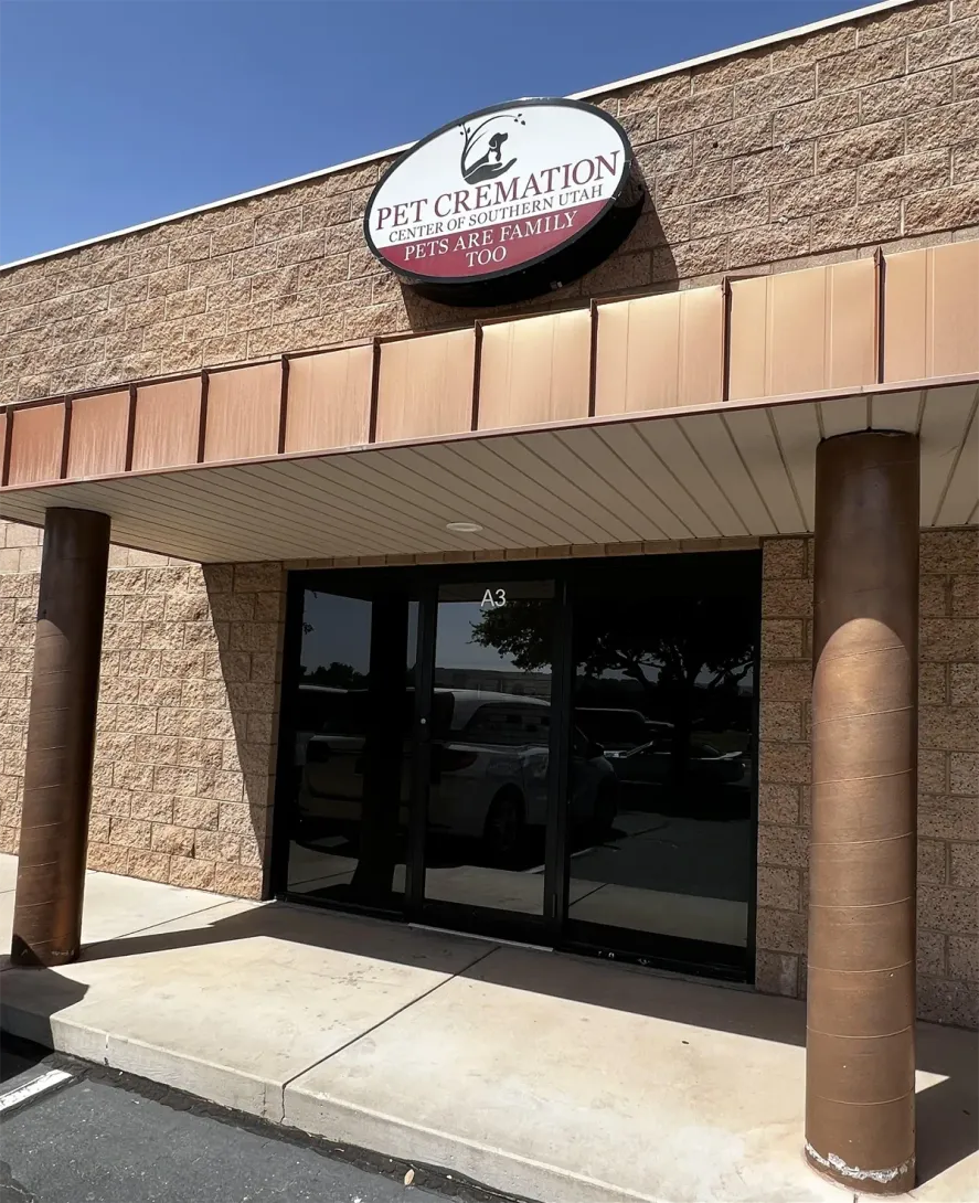 Storefront with an oval sign, tan awning, and dark glass doors under a blue sky.