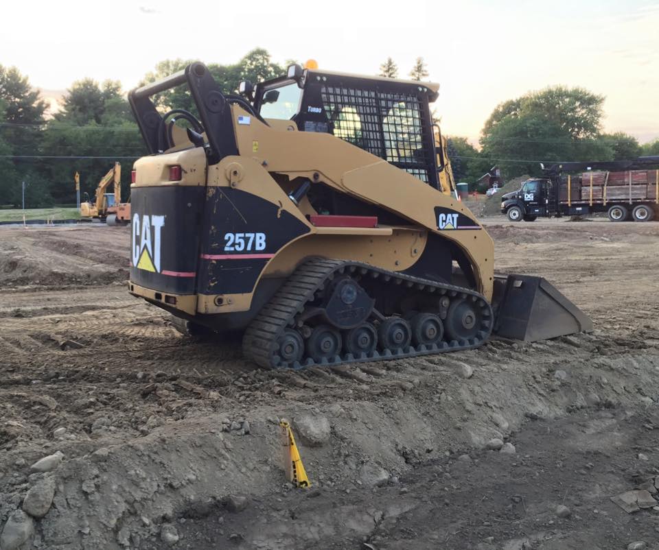 A Caterpillar 257B track skid steer on a dirt construction site.