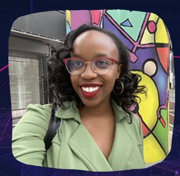A woman wearing glasses and a green jacket is smiling in front of a colorful wall.