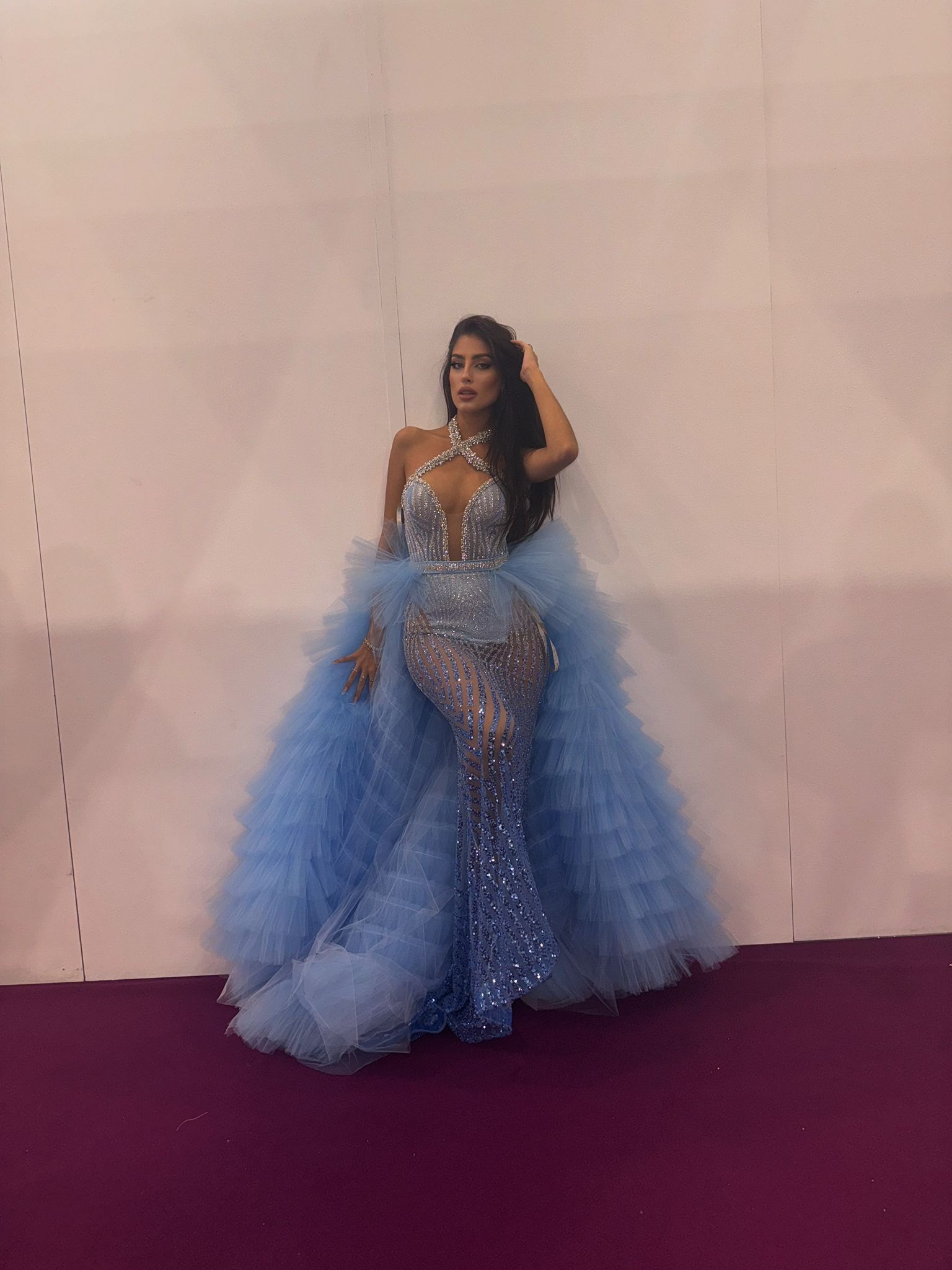 Una donna con un vestito blu è in piedi davanti a un muro.