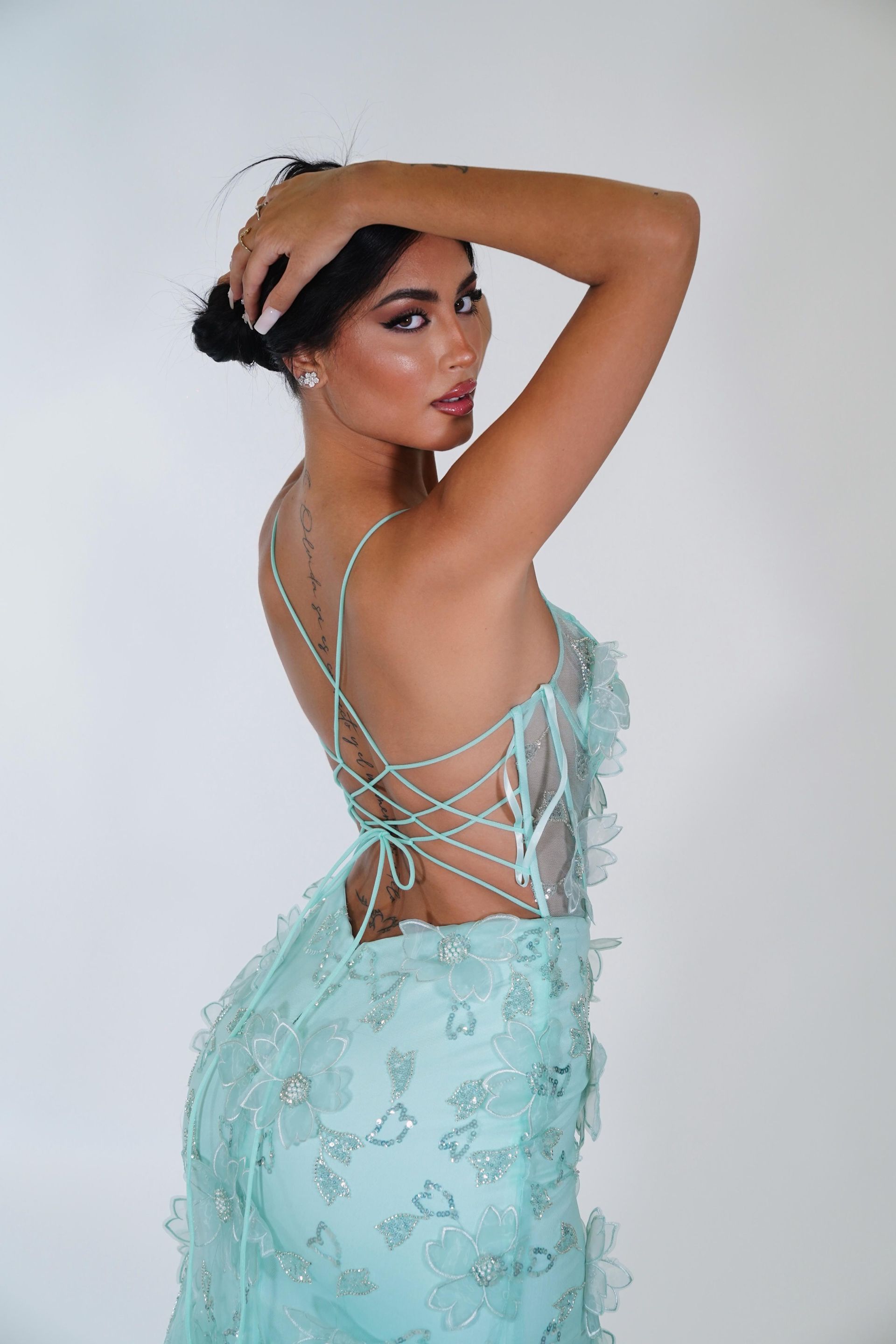 Una donna indossa un vestito azzurro con la schiena allacciata.