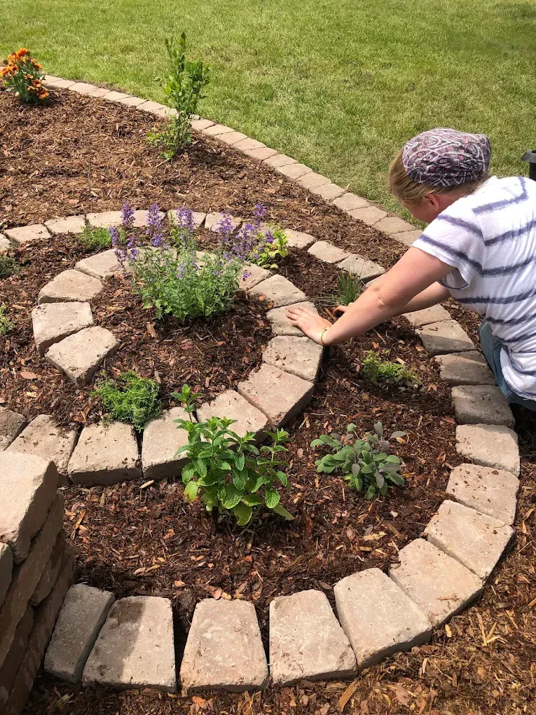 Person planting flowers in a circular stone garden bed