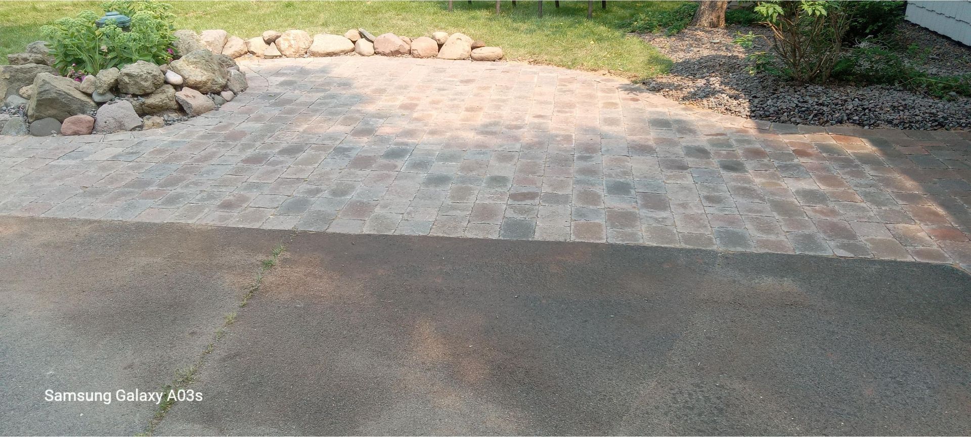 Stone-paved driveway beside a garden with rocks and greenery