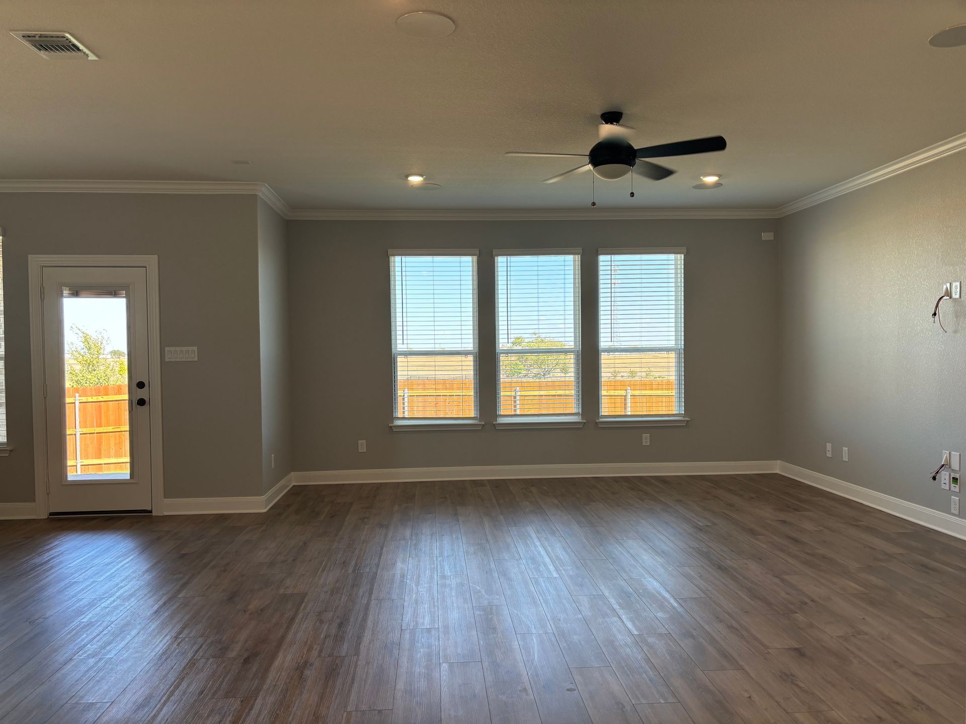 An empty living room with hardwood floors and a ceiling fan.