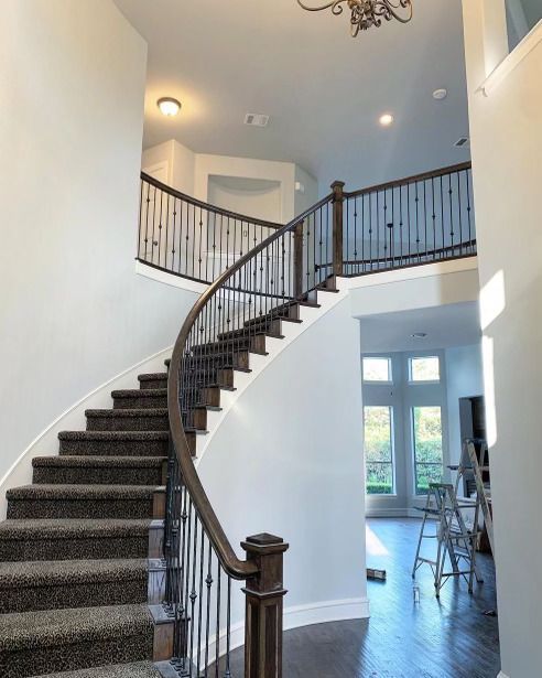 A curved staircase in a house with a wrought iron railing