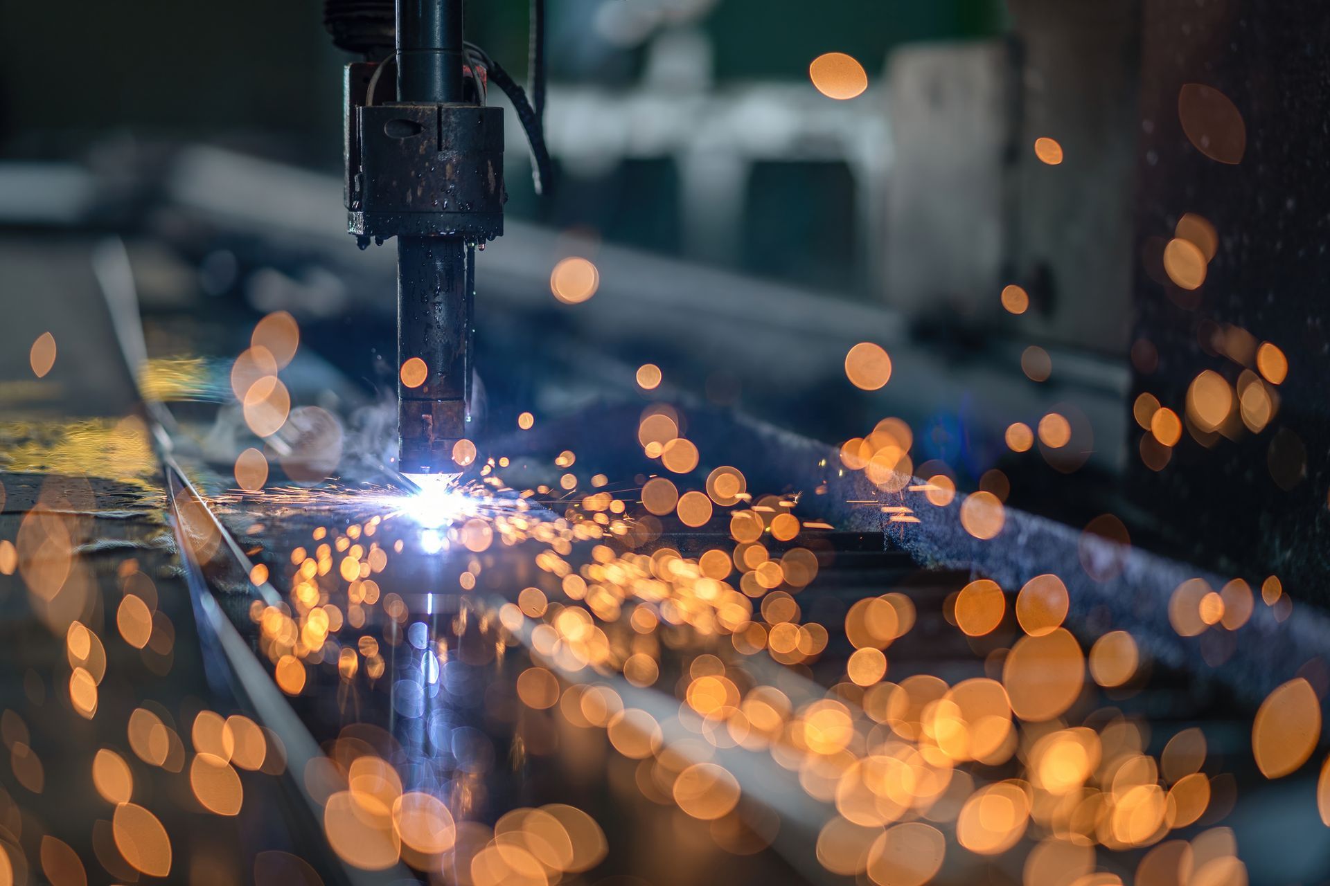 Close-up of a welding torch cutting metal with bright sparks flying across the surface.