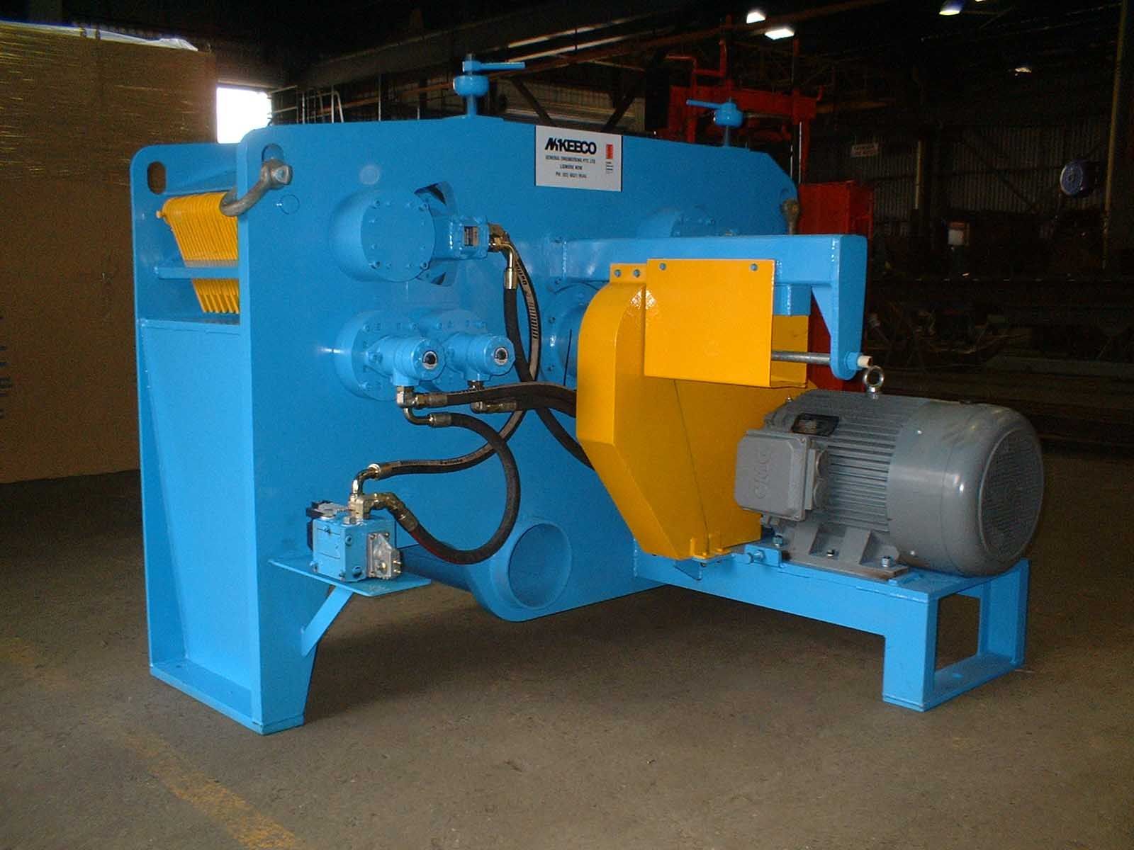 Blue industrial shear machine with yellow safety guard and grey motor.