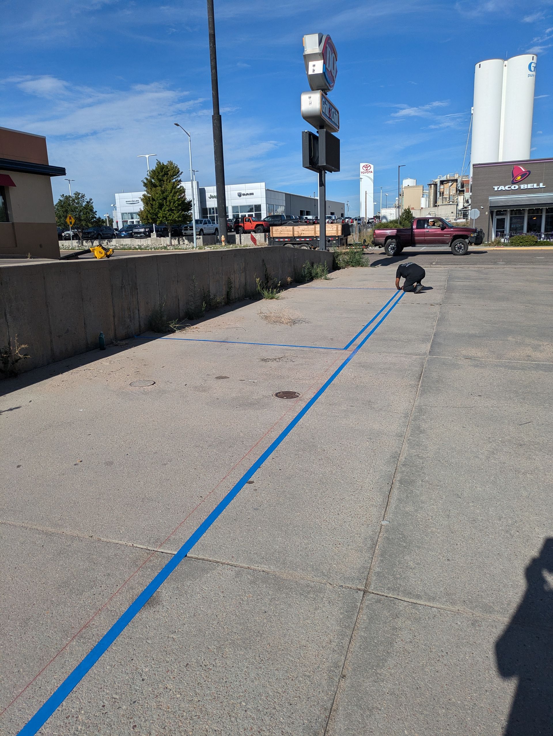 A person is walking a dog on a leash in a parking lot.