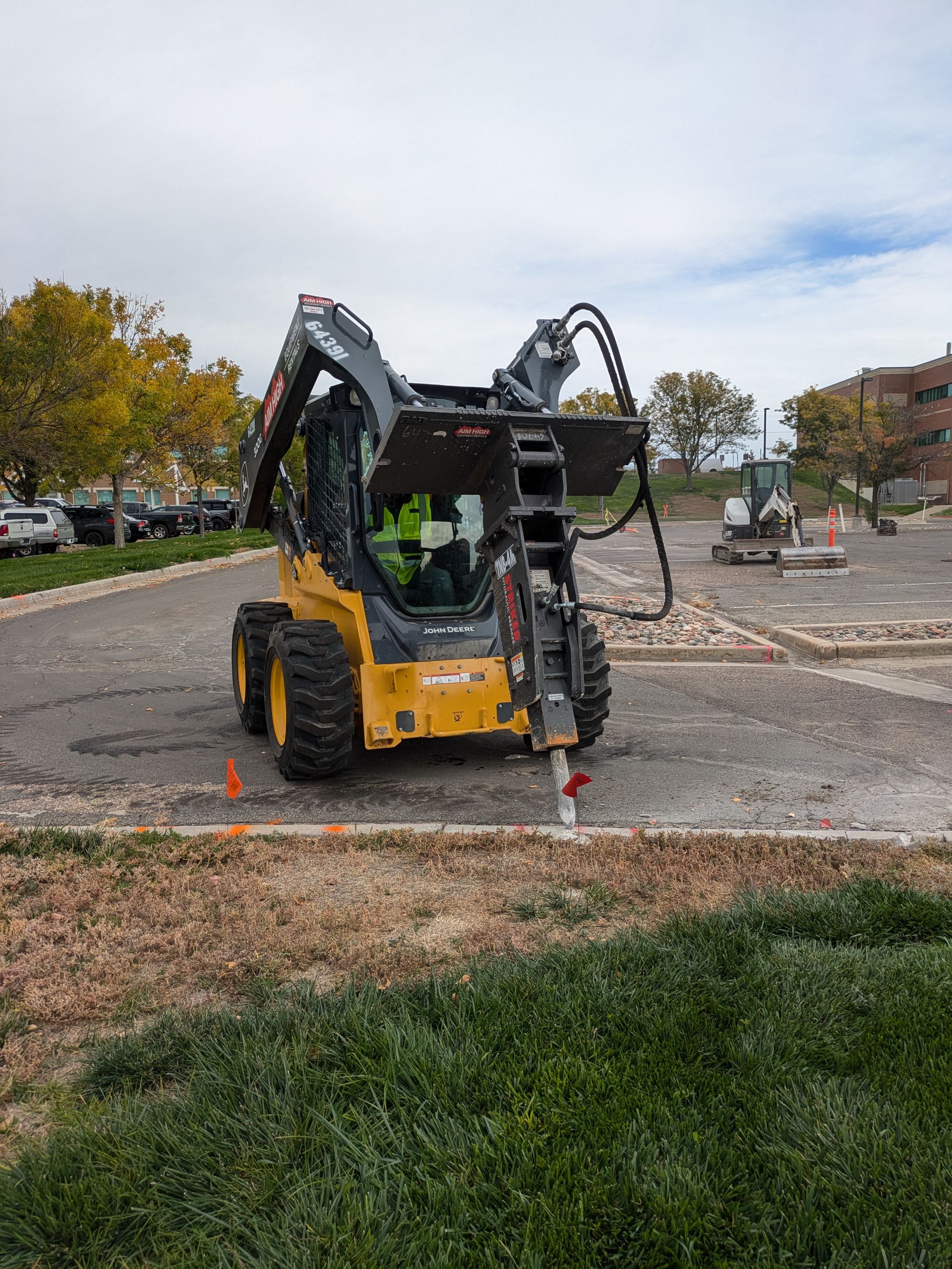 A man is driving a bulldozer in a parking lot.