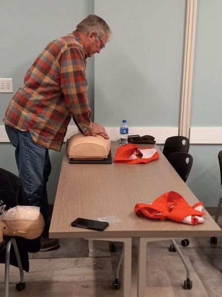 A man in a plaid shirt is putting a mannequin on a table