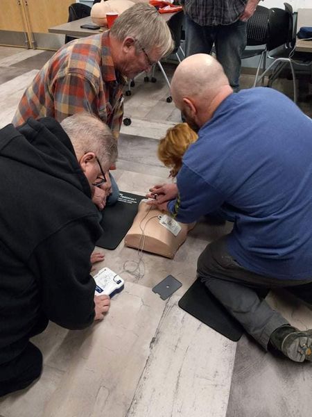 A group of men are kneeling on the floor looking at a mannequin.