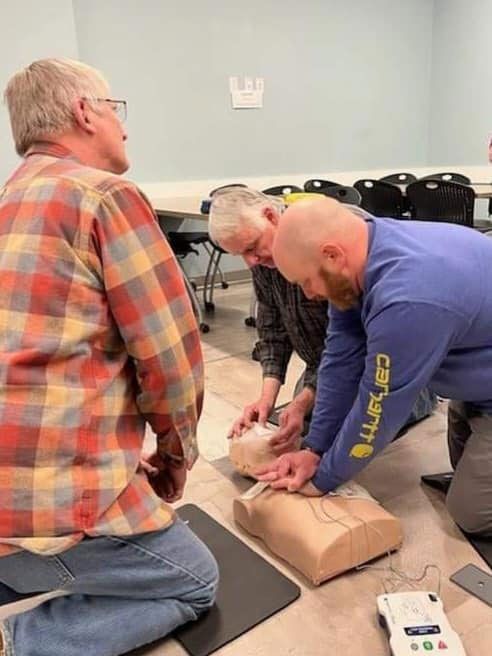 A man wearing a blue carhartt shirt is kneeling down